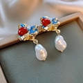 Detailed macro view of artistic blue enamel earrings with red beads and baroque pearls - Gold Texture Baroque Style / Gold with Blue