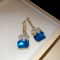 Elegant gold-toned earrings featuring blue rectangular gems and crystal flower accents. - Gold Flower / Blue