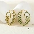 Detailed shot of gold leaf hoop earrings with green zircon inlay on a white stone base - Gold Green Zirconia (ER0776-D)