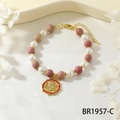 Detailed macro view of snake coin charm on pearl and natural stone beaded bracelet - Rhodonite