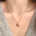 Golden rocking horse necklace with red enamel and white zircon on a grey sweater - Red Wing Horse Style
