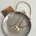 Golden horse pendant necklace with brown braided rope on a minimalist tray - Gold Horse Braided Rope Necklace