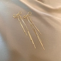 Détail macro de boucles d'oreilles à pompons dorés avec un nœud papillon sur soie - Gland Linéaire Nœud Papillon Or (E5021)
