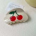 Close-up of cream acetate hair claw clip featuring red cherry patterns and sparkling rhinestones - Small / Beige