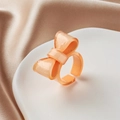 Detailansicht eines rosa Harz-Schleifenrings mit Goldglitzer auf Champagner-Seide - Champagner