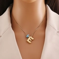 Détail du pendentif lettre E en or 18k avec perle œil bleu porté par mannequin - Lettre E Or