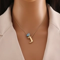 Détail du collier en or 18 carats avec lettre J et pendentif œil bleu sur costume - Lettre J Or