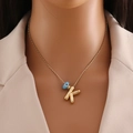 Détail du collier en or avec pendentif lettre K et œil maléfique bleu porté sur modèle - Lettre K Or
