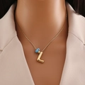 Gros plan du collier en or 18 carats avec pendentif lettre L et perle œil bleu sur mannequin - Lettre L Or
