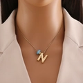 Détail du collier plaqué or 18k avec pendentif lettre N et breloque œil bleu sur mannequin - Lettre N Or