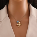 Gros plan d'un collier doré 18k avec pendentif lettre X et perle bleue sur un mannequin - Lettre X Or