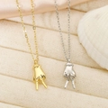 Detailed macro view of gold and silver peace sign gesture pendant necklaces on fabric - V Sign Gesture / Gold