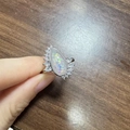 Detailopname van een peervormige opaalring met diamanten halo aan de hand - US 6 / Zilver