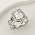 Elegant square moissanite ring with a halo setting and split shank on a beige pedestal - US 6 / Silver