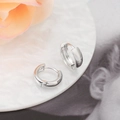 Detailed macro view of polished silver U-shaped huggie earrings on a stylish tray - Silver