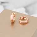 Elegant polished rose gold U-shaped hoop earrings on a textured gold display stand - Rose Gold