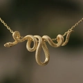Elegante vergulde slangenhanger ketting met gedetailleerde schubben en fijne kruisring - Goud