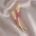 Goldene Weizenähren-Brosche mit eleganten Zirkonia-Steinen im rosa-magenta Farbverlauf - Weizenähre Brosche