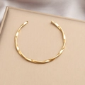 Golden Mobius twist bangle in polished titanium steel with an open adjustable design - Gold