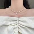 Franse stijl parelketting met gouden munt hanger, getoond op een vrouwelijk model - Parel Portret Stijl
