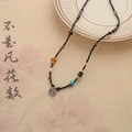 Etnische kralenketting met zwarte kralen en een vintage zilveren leeuwenhanger - Leeuwendans Ronde Schijf Ketting