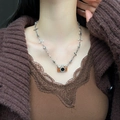 Schicke Silberhalskette mit orangefarbenem Kamera-Anhänger und brauner Quaste am Strickpulli - Silber Kreuz Kamera Halskette