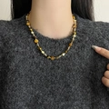 Kralenketting van tijgeroog en goudkleurige kralen gedragen op een donkergrijze gebreide trui - Maillard Tijgeroog Kralenketting
