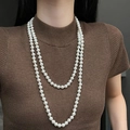 Dubbellaagse lange witte ronde parelketting voor dames gedragen op bruine trui - Dubbellaagse Lange Parelketting