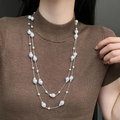 Dubbellaagse lange ketting met witte barokparels gestyled op een bruine trui - Verstelbare Parelketting