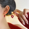 Boucles d'oreilles dorées avec pendentifs en perles d'agate rouge portées par un mannequin - Boucles d'oreilles en Perles Rouge Ancora