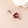 Silver devil navel ring with red heart-shaped gemstone and horn accents on pink background - Little Devil Heart Red Zirconia Silver