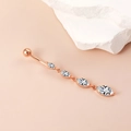 Roségouden navelpiercing met marquise geslepen kristallen op een gladde roze ondergrond - Marquise Kwastje Stijl / Roségoud