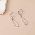Boucles d'oreilles ovales argentées géométriques creuses sur fond minimaliste beige - Argent