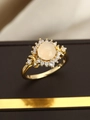 Nahaufnahme eines Vintage-Goldrings mit rosa ovalem Cabochon und Zirkonia-Heiligenschein - US 6 / Gold