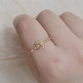 Vista macro de un anillo dorado con una gema amarilla cuadrada y detalles de halo brillante - Abierto Ajustable / Dorado