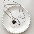 Collier argenté avec pendentif cœur en œil de tigre brun sur une assiette en porcelaine blanche - Oeil de Tigre (Cœur)