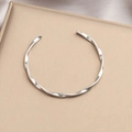 Silver twisted spiral stainless steel bangle with polished finish on a display stand - Silver