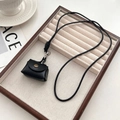 Mini zwarte lederen pouch met geweven koord en zilveren sluiting op houten dienblad - Zwarte Mini Tas Ketting