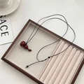 Collier vintage avec pendentif gourde en bois rouge foncé et cordon noir sur plateau - Collier Pendentif Calebasse en Santal Rouge