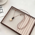 Collier ethnique avec pendentif calebasse crème et cordon marron ajustable - Collier Sac d'Argent en Graine de Bodhi