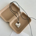 Minimalistische zilveren hartketting met verstelbaar zwart koord op kraftpapier tray - Leren koord / Zilver