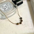 Elegante gouden slangenketting met vijf natuurlijke tijgeroogkralen op witte stoffen - Tijgeroog Kralenketting