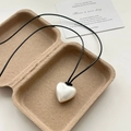 Minimalistische crèmewitte hartjesketting met zwart koord op een rustiek dienblad - Mat Zilver (Kunstparel)