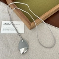 Minimalistische lange Leder- und Metallkette mit grauem Anhänger auf Stoff - Graue Lederkette