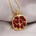 Golden pomegranate pendant necklace with deep red garnet stones on silk background - Gold Red