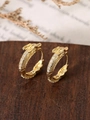 Detailed close-up of dragon head hoop earrings with shimmering diamonds on wood base - Gold