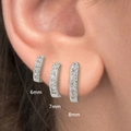 Three sizes of silver huggie earrings with cubic zirconia stones worn on an ear - 6mm / Silver with White Rhinestone