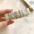 Detailed macro of white and gold tweed fabric texture on an elegant rectangular hair clip - White