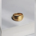 Golden croissant dome ring with horizontal wavy ripples and a polished metal finish - Pleated Metallic Style