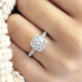 Eleganter silberner Verlobungsring mit rundem Hauptstein und Halo-Fassung an der Hand - US 5 / Weißgold